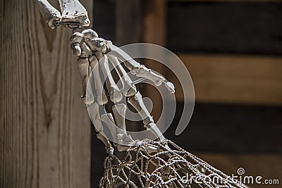 Dead pirates hand - old and dusty fake skeleton hand tangled in fishing net against blurry background Stock Photo