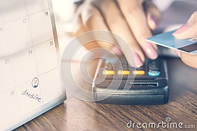 Deadline calendar note with blur background of business woman hand counting her debt on calculator with hand holding credit card Stock Photo