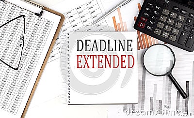 DEADLINE EXTENDED text on notebook with clipboard and calculator on a chart background Stock Photo
