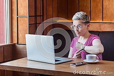 Deadline! Portrait of warning attractive young bossy girl with blonde short hair is sitting in cafe and making video call on Stock Photo