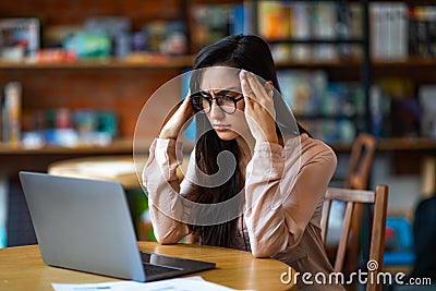 Deadline stress. Exhausted latin woman tired after work on laptop, having headache, sitting at table in cafe Stock Photo