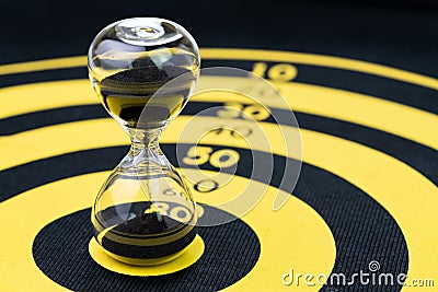 Deadline, time management or goal and target with time specific concept, hourglass or sandglass on yellow circle dartboard Stock Photo