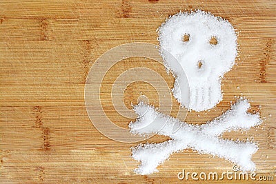 Deadly sugar addiction suggested by spilled white sugar crystals forming a skull on a wooden table Stock Photo