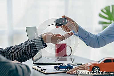 The dealer or dealership gives the car keys to the new owner. Customer signs insurance document or rental car Stock Photo