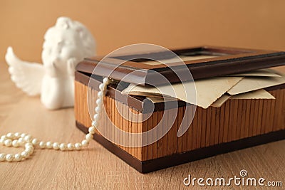 Dear to heart memorabilia in an old wooden box, pearl beads, stack of retro photos, vintage photographs of 40s - 50s, concept Stock Photo