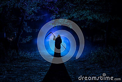 Death with a scythe in the dark misty forest. Woman horror ghost holding reaper in forest Stock Photo