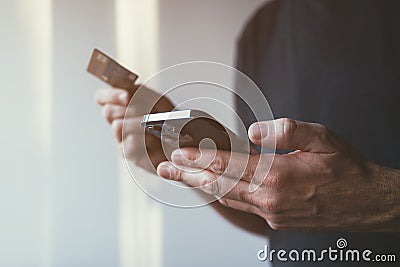 Debit card and mobile phone app online purchase, closeup of male hands using smartphone to complete financial transaction on Stock Photo