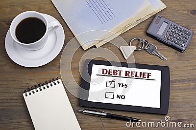 Debt Relief. Text on tablet device on a wooden table Stock Photo
