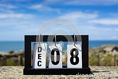 Dec 08 calendar date text on wooden frame with blurred background of ocean. Stock Photo