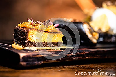 Decadent slice of cake on a rustic wooden board finished with a drizzle of the sweet topping Stock Photo