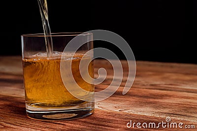 From a decanter, whiskey is poured into a glass Stock Photo