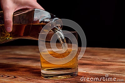 From a decanter, whiskey is poured into a glass Stock Photo