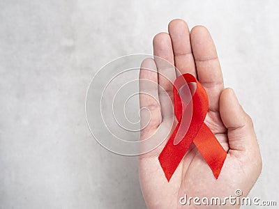 01 December European male hand with red ribbon symbol of HIV AIDS. Top view with copy space Stock Photo