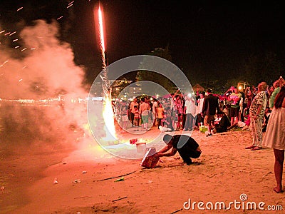 31 december 2016 sihanoukville beach cambodia, adult asian man kneeling on beach under fireworks explosion Editorial Stock Photo