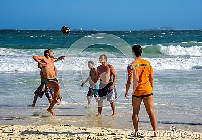 6 December 2016. Three brazilian men playing beach football in motion on the background of waves at Copacabana beach Editorial Stock Photo