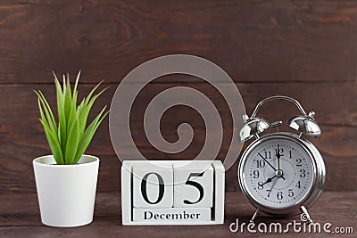 December 5 on a white wooden calendar next to an alarm clock on a dark wooden background Stock Photo