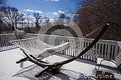 Frozen macrame hammock on a snow covered residential deck facing sun Stock Photo