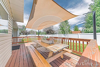 Deck of a house with wooden chairs and table under a shade sail Stock Photo