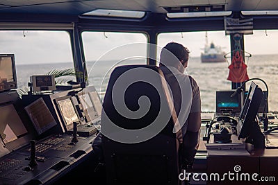 Deck navigation officer on the navigation bridge. He looks at radar screen Stock Photo