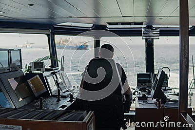 Deck navigation officer on the navigation bridge. He looks to sea Stock Photo