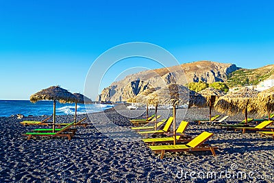 Deckchairs on peaceful morning beach Kamari Black beach Santorini Greece Stock Photo