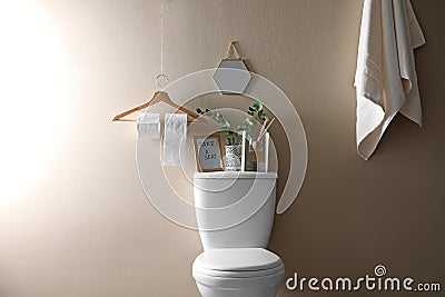 Decor elements, necessities and toilet bowl near beige wall. Bathroom Stock Photo