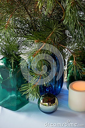 The decor of the table in the restaurant.Bottles of green and blue glass, mirror balls and spruce paws. Stock Photo