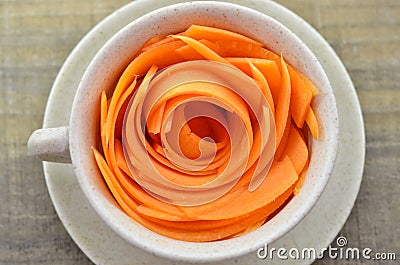 Decorate cup with slices carrots on wooden table Stock Photo