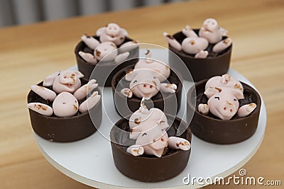 Decorated candies, happy cute pink pigs playing in the mud Stock Photo