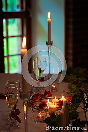 Decorated Christmas table with candles, candlesticks, tealight candles, candle holders, artificial plants, white tablecloth and Stock Photo