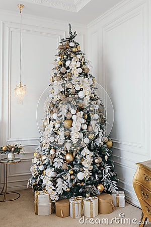 Decorated Christmas tree with gift boxes in white room Stock Photo