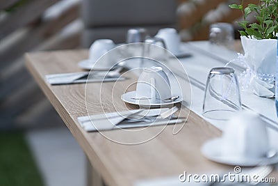 Decorated garden table set with epty coffecups and unused water glasses Stock Photo