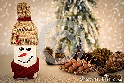 Decorated handmade wooden snowman with pine cones on the snowy background Stock Photo