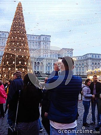 Decorated huge Christmas tree, lights, decorations, hot wine, hot chocolate, presents and people wandering at the Christmas market Editorial Stock Photo