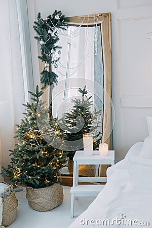 Decorated mirror and live Christmas tree with lights. New year's interior, festive atmosphere, decor, garlands Stock Photo