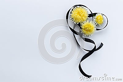 Decoration from black funeral ribbon with yellow flowers. Stock Photo