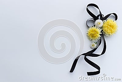 Decoration from black funeral ribbon with yellow flowers. Stock Photo