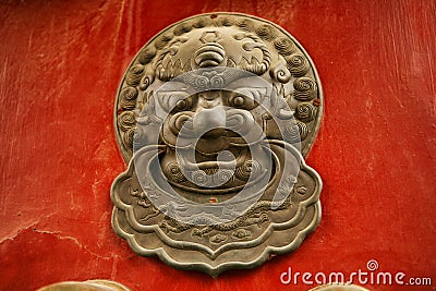 The decoration element of a red wooden door in the form of a lion`s head in the Forbidden City, Beijing, China Stock Photo