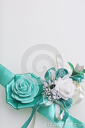 Decoration on hand in the form of a rose of emerald color, sewn to a satin ribbon. Near the wedding boutonniere. On a white backgr Stock Photo