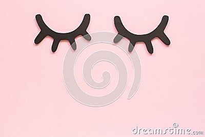 Decorative black wooden eyelashes, closed eyes on pink background. Concept Good night or Sweet dreams Greeting card Top view Copy Stock Photo