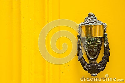 Decorative bronze door handle on a yellow painted door. Malta Stock Photo