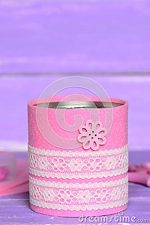 Decorative can on wooden background. Old tin can decorated with pink felt, white lace and flower button. Easy and cheap Stock Photo