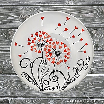 Decorative ceramic plate, hand painted with acrylic paints on a wooden background. A square photo closeup Stock Photo