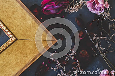 Classic golden picture frame and flowers on dark backdrop. Framer workshop concept. Stock Photo