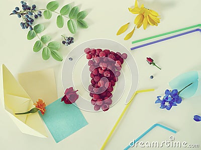 Decorative composition - a glass of fresh raspberries, cocktail tubules, fresh flowers, petals and berries on a light background Stock Photo