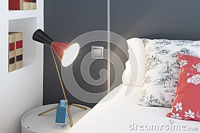 Decorative detail of a bedroom with matching cushions with a lamp and gray painted walls Stock Photo