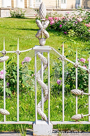 Decorative element of vintage forged white fence with garlands of flowers Stock Photo