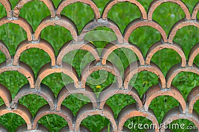 Decorative fence made of semicircular bricks, arranged in a staggered pattern, creating a unique design with gaps between the Stock Photo