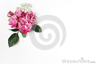 Decorative floral composition with pink roses, green leaves and and baby`s breath Gypsophila flowers on white table Stock Photo