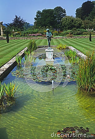 A decorative garden pool with water lilies and a classicl statue in the centre of a large lawn Editorial Stock Photo